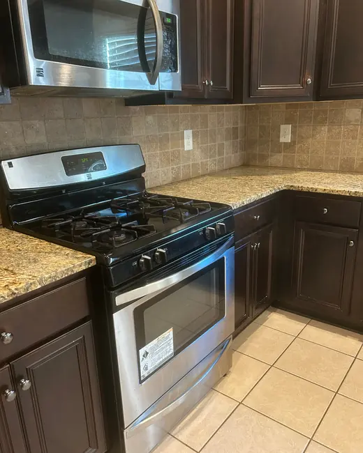 Kitchen with a stainless range, granite counters and a tile backsplash after cleaning