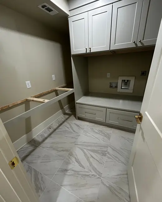 Laundry and mud room with white cabinets and a marble tile floor