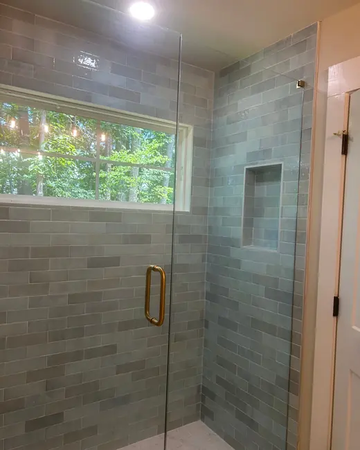 Tiled walk-in shower with a glass door and a built-in niche, cleaned