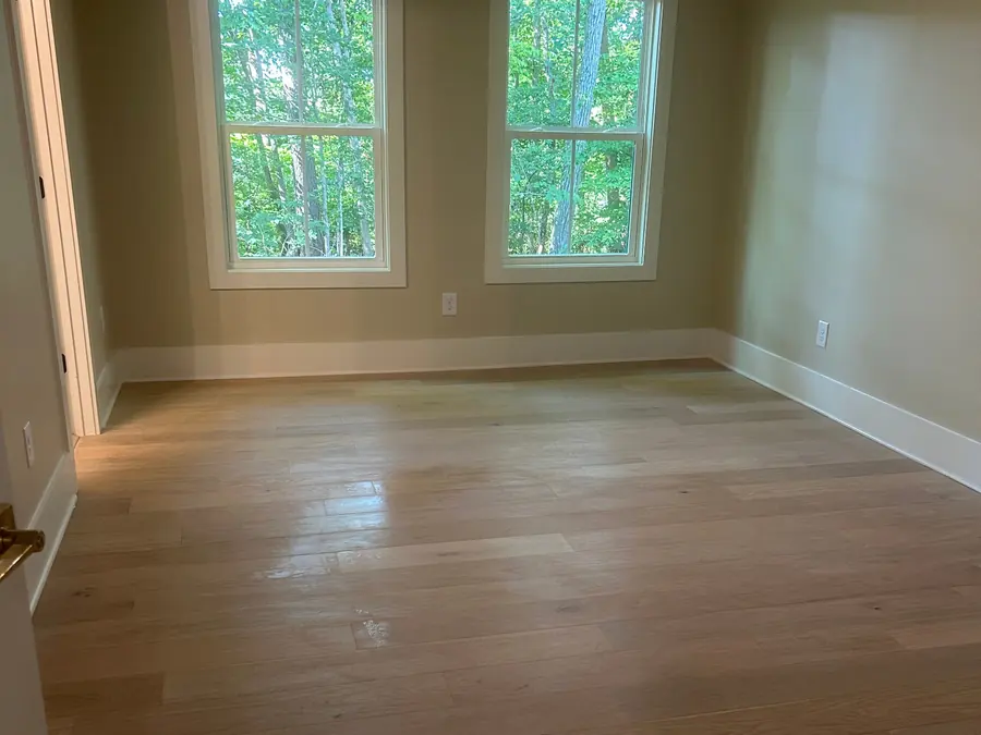 Bright empty living room with clean wood floors and tall windows after a move-out clean