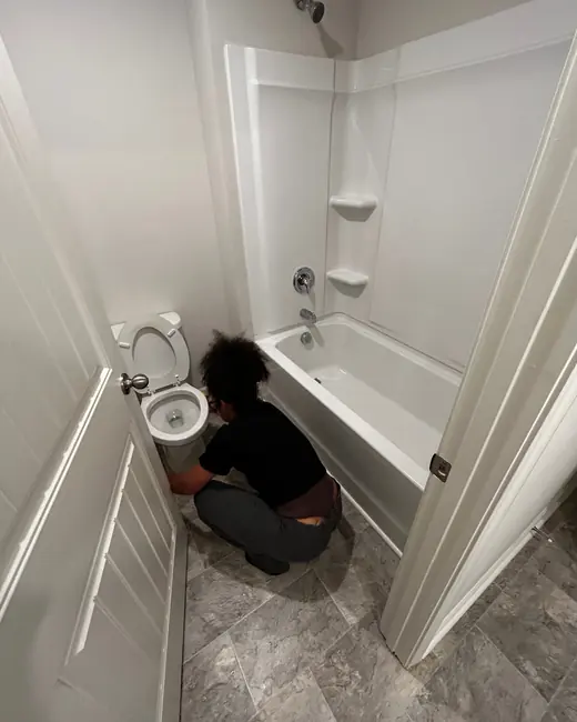 A team member cleaning around a bathtub and toilet on a job